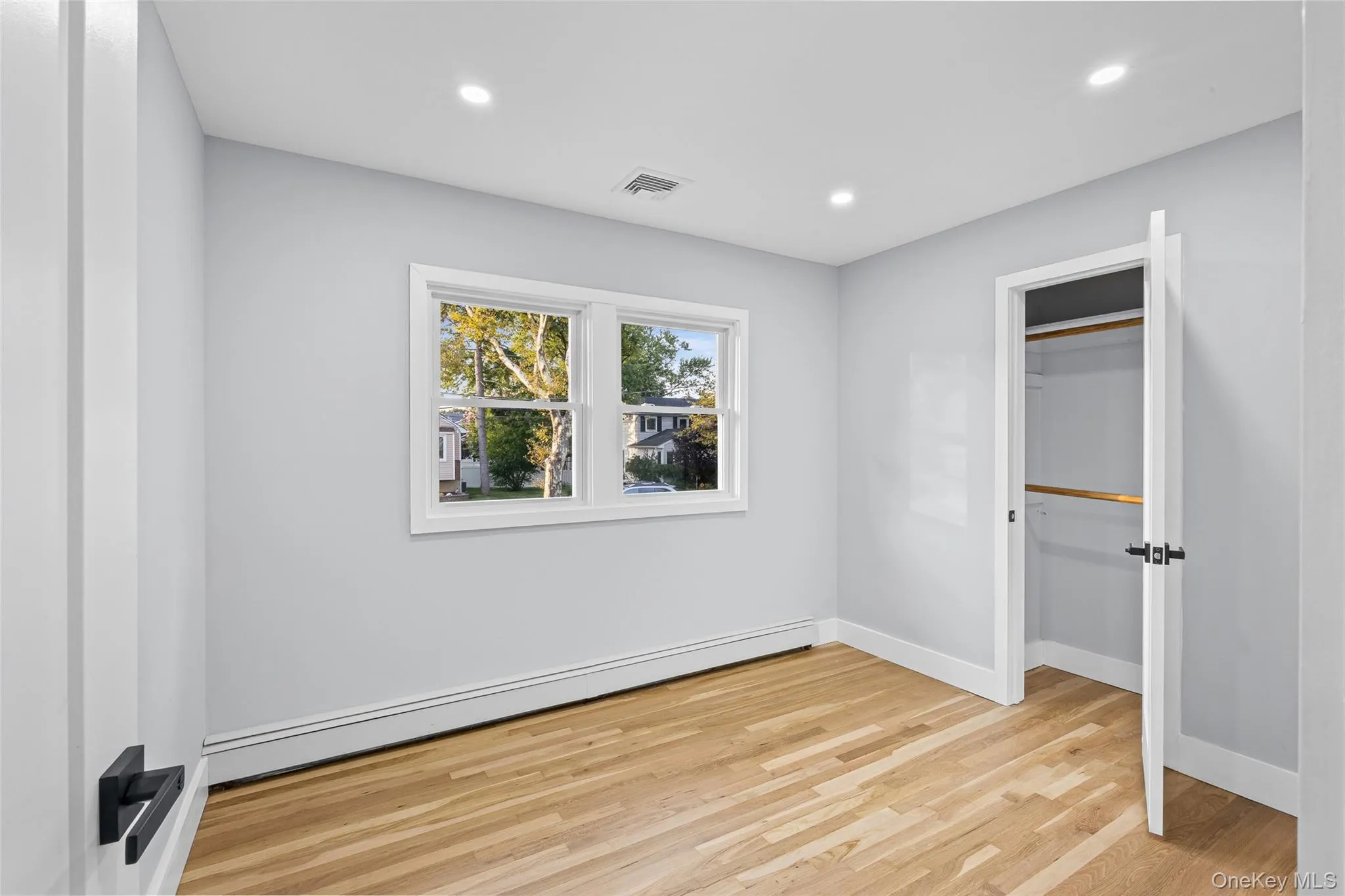 Unfurnished bedroom with a baseboard heating unit, light wood-style floors, recessed lighting, and a closet Unfurnished bedroom with a baseboard heating unit, light wood-style floors, recessed lighting, and a closet