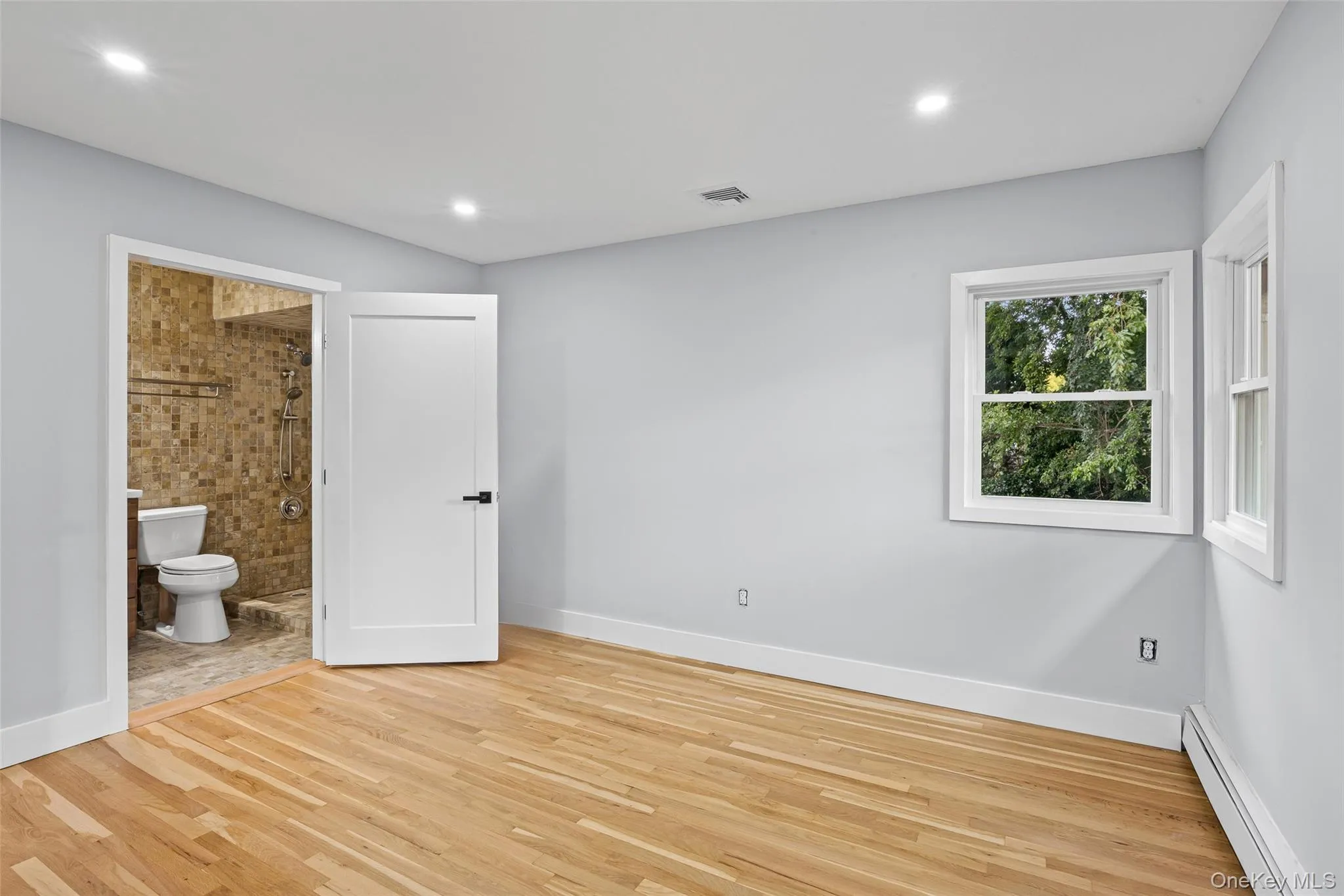 Unfurnished bedroom featuring a baseboard radiator, light wood-type flooring, recessed lighting, and ensuite bathroom Unfurnished bedroom featuring a baseboard radiator, light wood-type flooring, recessed lighting, and ensuite bathroom