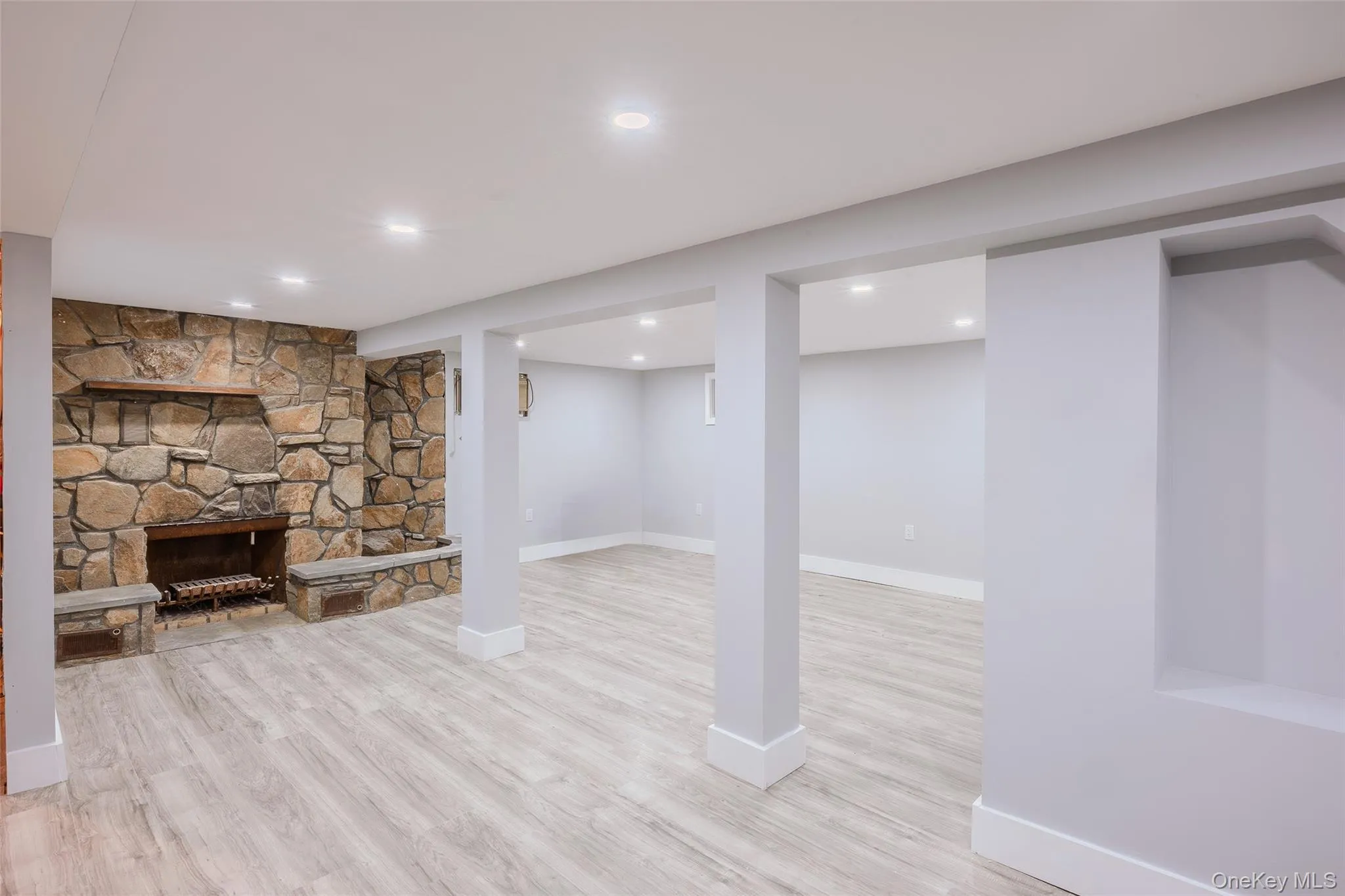 Finished below grade area featuring a stone fireplace, light wood-type flooring, and recessed lighting Finished below grade area featuring a stone fireplace, light wood-type flooring, and recessed lighting