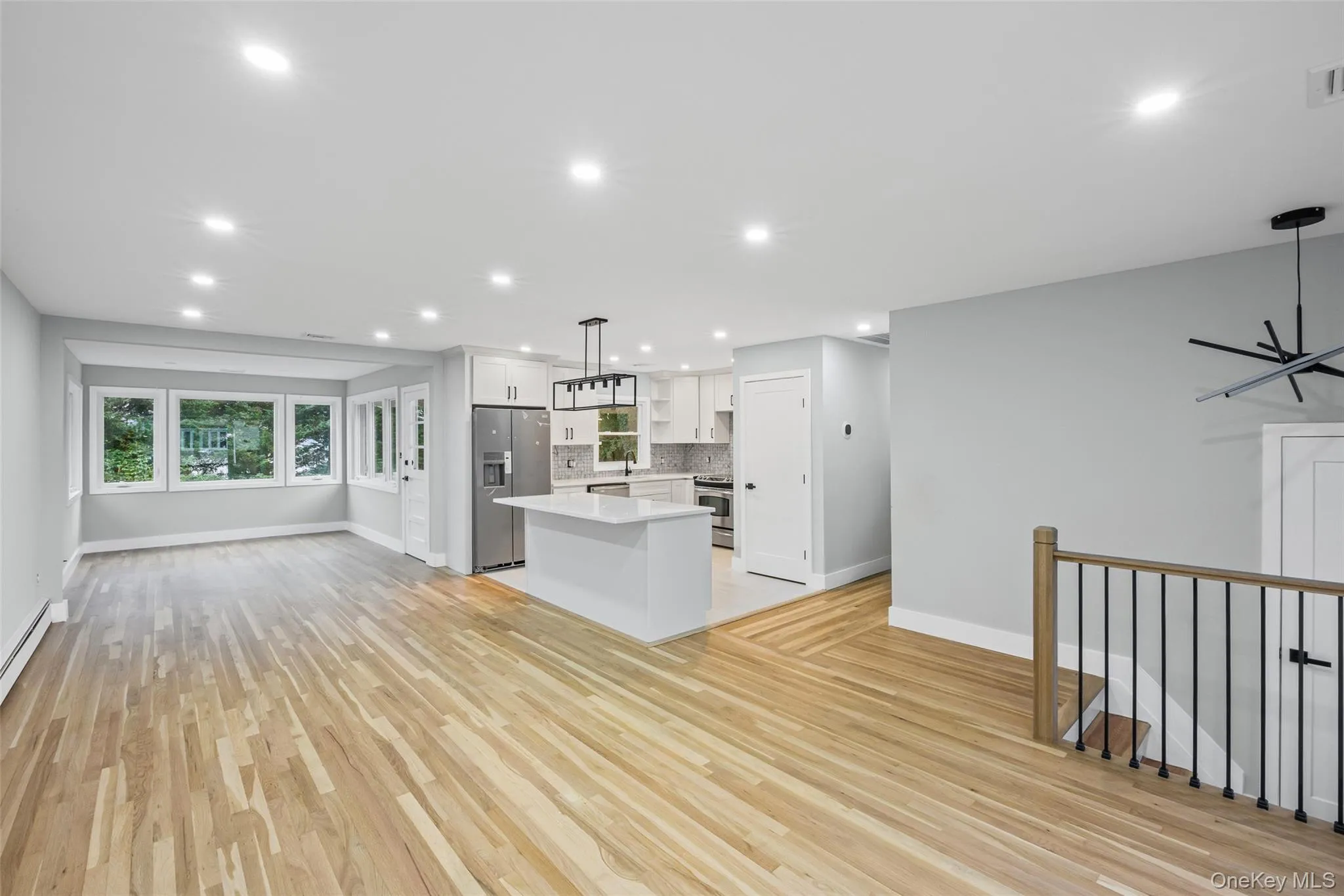 Kitchen with open floor plan, a kitchen island, hanging light fixtures, white cabinetry, and stainless steel appliances Kitchen with open floor plan, a kitchen island, hanging light fixtures, white cabinetry, and stainless steel appliances