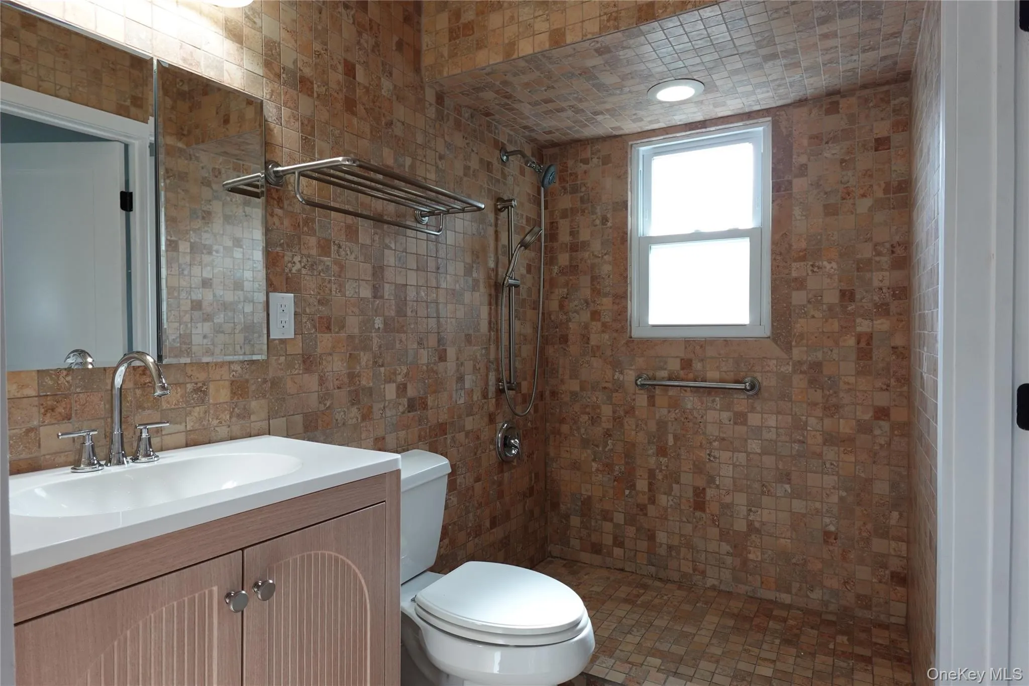 Full bathroom featuring tile walls, vanity, a tile shower, and backsplash Full bathroom featuring tile walls, vanity, a tile shower, and backsplash