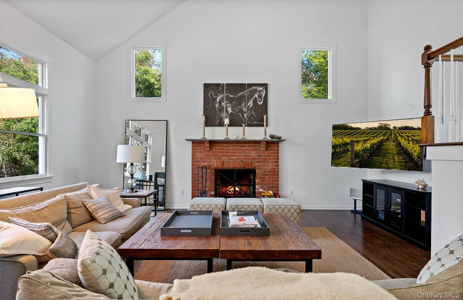 Living room featuring a fireplace, wood finished floors, and high vaulted ceiling Living room featuring a fireplace, wood finished floors, and high vaulted ceiling