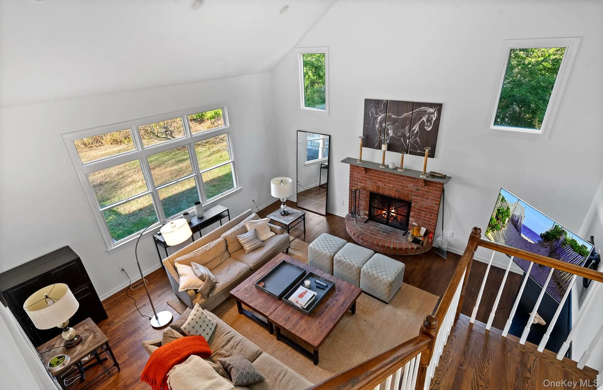 Living area featuring a brick fireplace, high vaulted ceiling, and wood-type flooring Living area featuring a brick fireplace, high vaulted ceiling, and wood-type flooring
