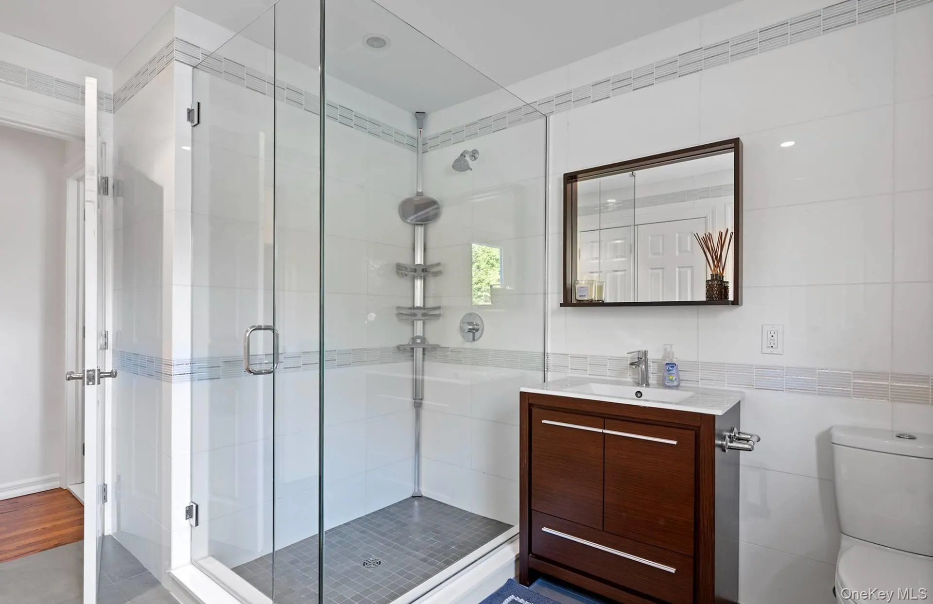 Bathroom featuring a shower stall, vanity, and tile walls Bathroom featuring a shower stall, vanity, and tile walls