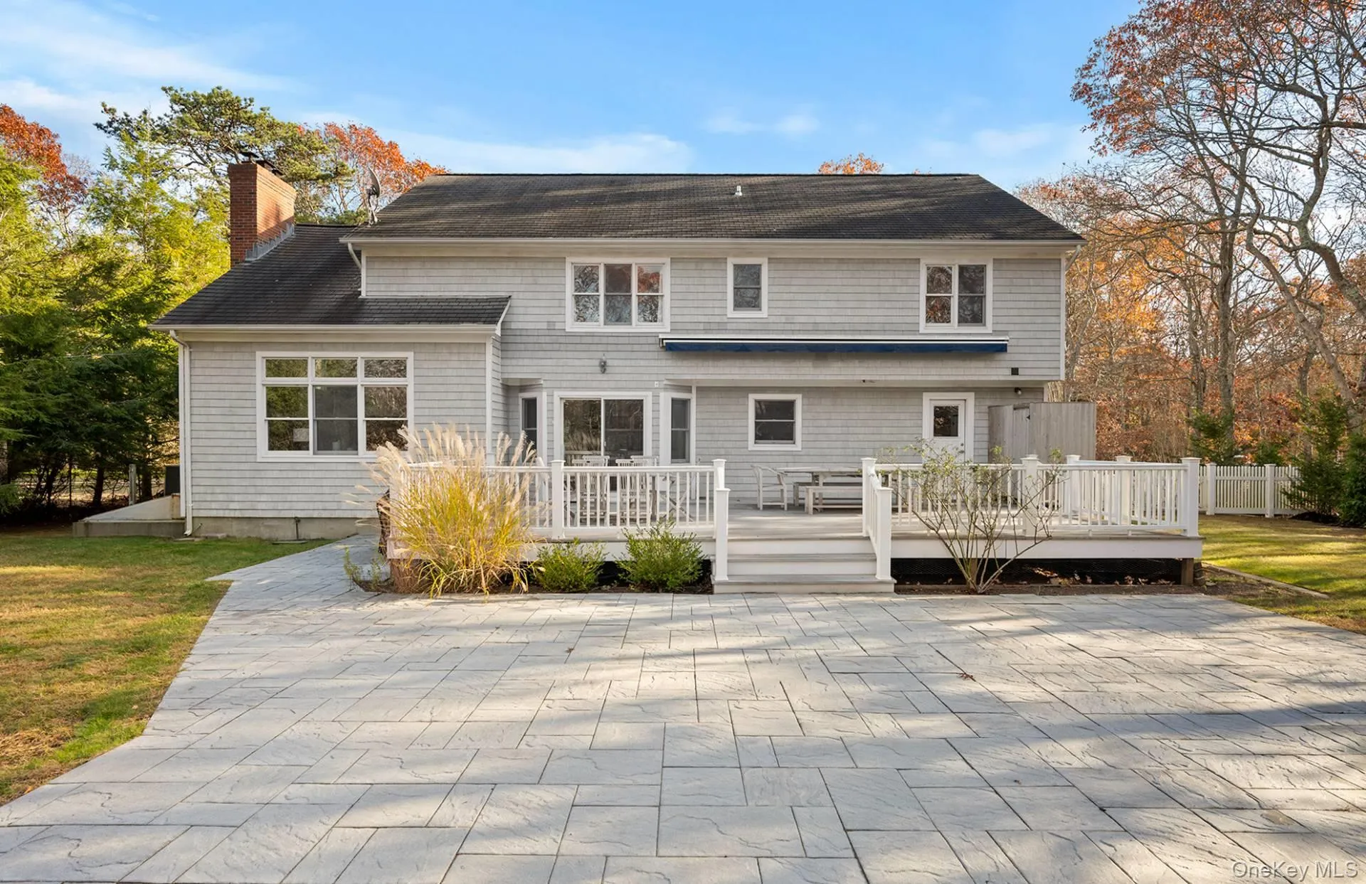 Back of property with a chimney, a wooden deck, and a lawn Back of property with a chimney, a wooden deck, and a lawn