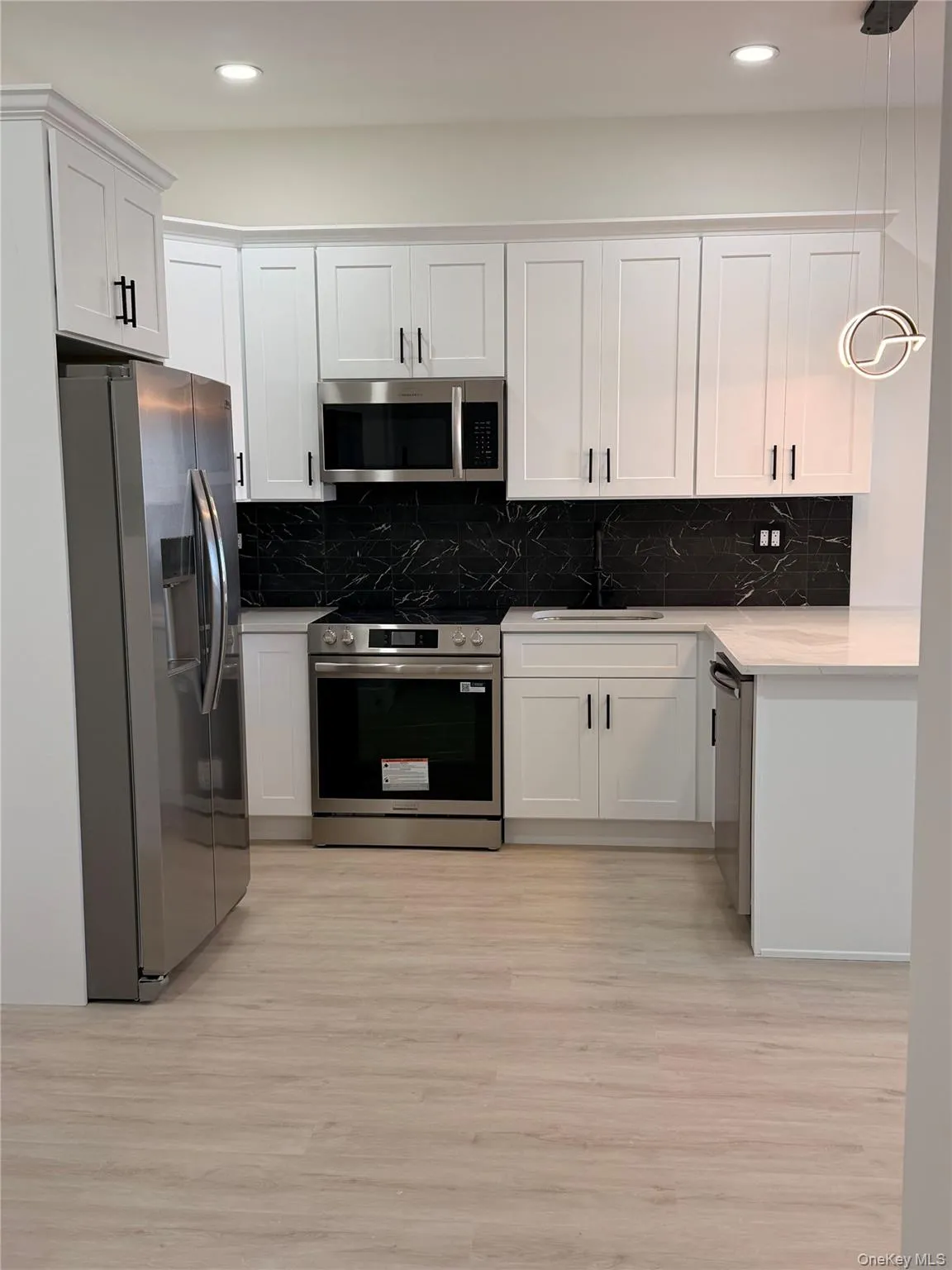 Kitchen featuring stainless steel appliances, white cabinetry, pendant lighting, light stone counters, and recessed lighting Kitchen featuring stainless steel appliances, white cabinetry, pendant lighting, light stone counters, and recessed lighting
