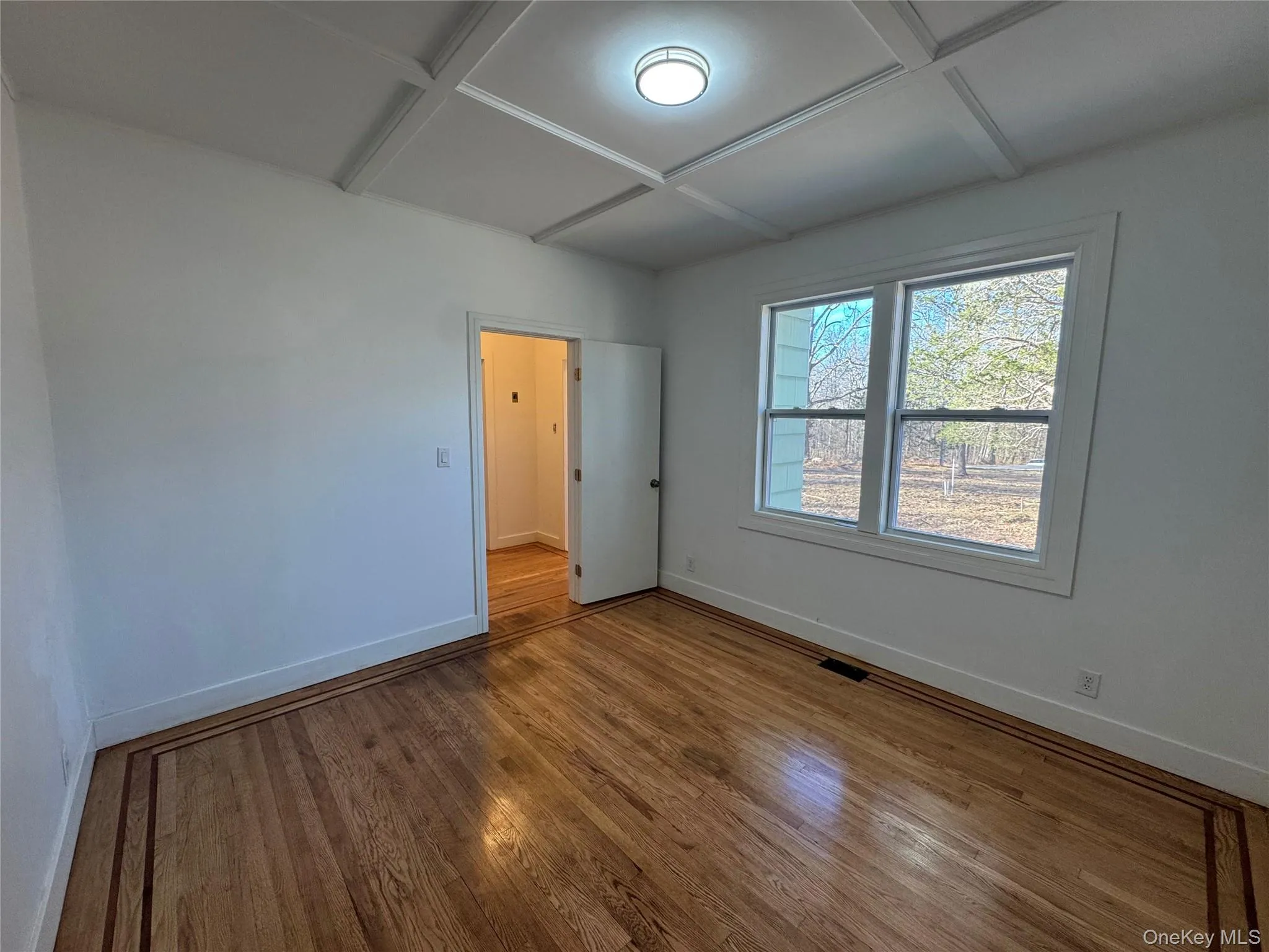 Unfurnished bedroom featuring hardwood / wood-style flooring and coffered ceiling Unfurnished bedroom featuring hardwood / wood-style flooring and coffered ceiling