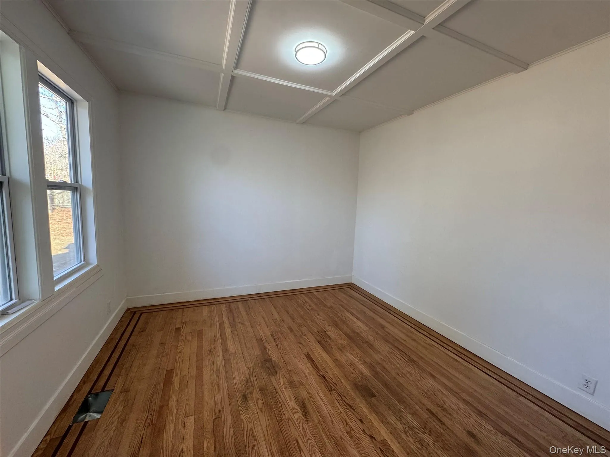 Unfurnished room with wood finished floors and coffered ceiling Unfurnished room with wood finished floors and coffered ceiling