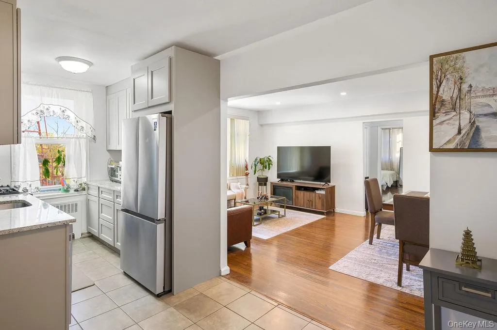 Kitchen with light stone counters, freestanding refrigerator, light tile patterned flooring, open floor plan, and white cabinetry Kitchen with light stone counters, freestanding refrigerator, light tile patterned flooring, open floor plan, and white cabinetry