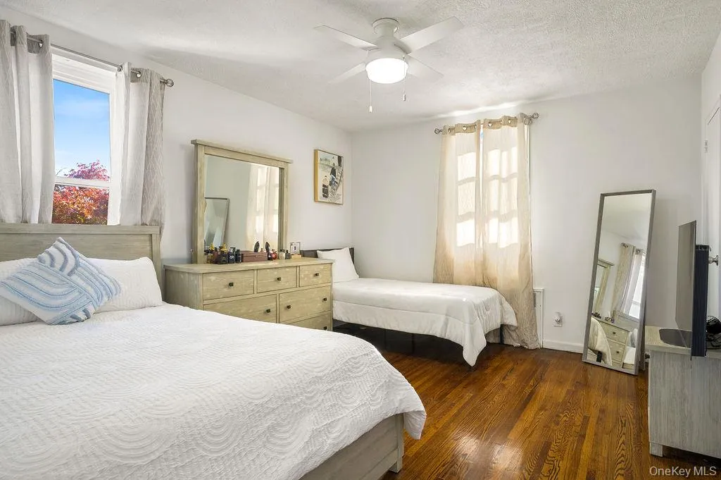 Bedroom featuring multiple windows, dark wood-style floors, a ceiling fan, and a textured ceiling Bedroom featuring multiple windows, dark wood-style floors, a ceiling fan, and a textured ceiling