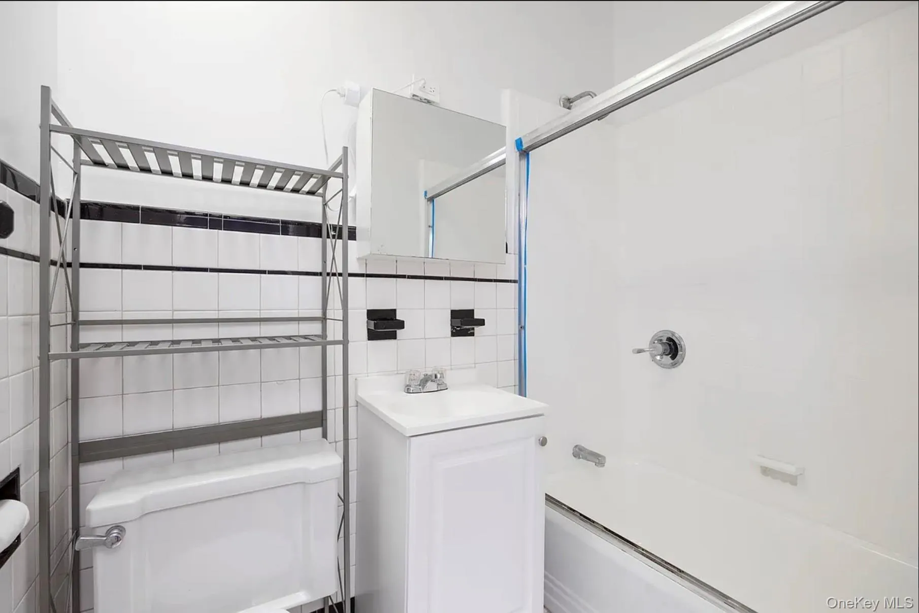 Full bath with tile walls, shower / bath combination with glass door, vanity, and decorative backsplash Full bath with tile walls, shower / bath combination with glass door, vanity, and decorative backsplash