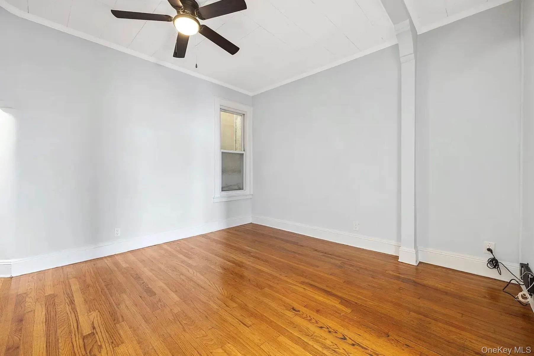 Empty room with ornamental molding, hardwood / wood-style flooring, and ceiling fan Empty room with ornamental molding, hardwood / wood-style flooring, and ceiling fan