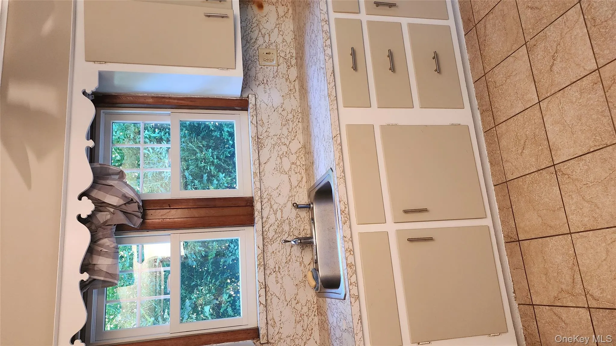 Kitchen featuring light countertops, cream cabinets, and light tile patterned floors Kitchen featuring light countertops, cream cabinets, and light tile patterned floors