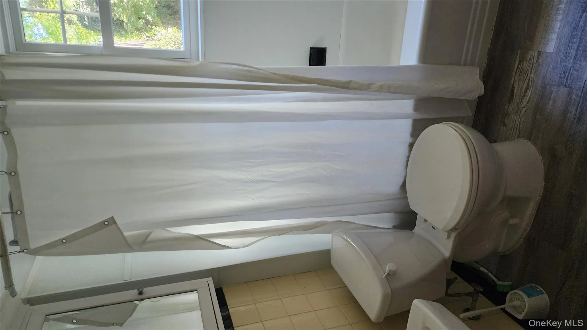 Bathroom with dark wood-style flooring, shower / tub combo with curtain, and tile walls Bathroom with dark wood-style flooring, shower / tub combo with curtain, and tile walls