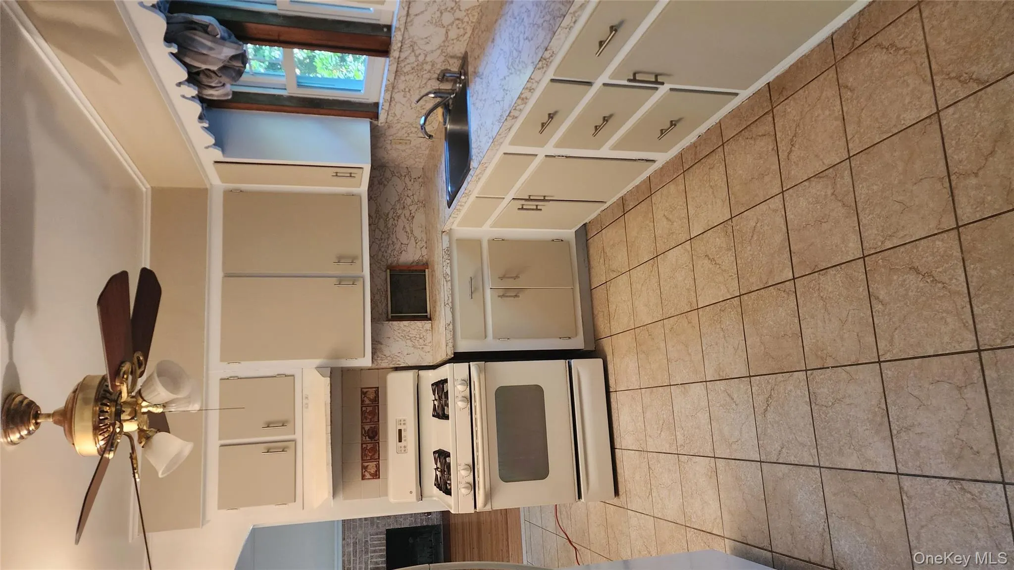 Kitchen featuring range, light countertops, ceiling fan, and a brick fireplace Kitchen featuring range, light countertops, ceiling fan, and a brick fireplace