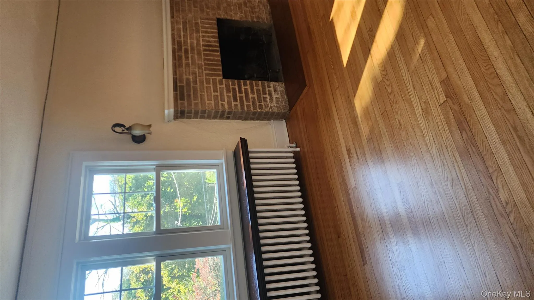 Unfurnished living room with radiator, a fireplace, and wood-type flooring Unfurnished living room with radiator, a fireplace, and wood-type flooring