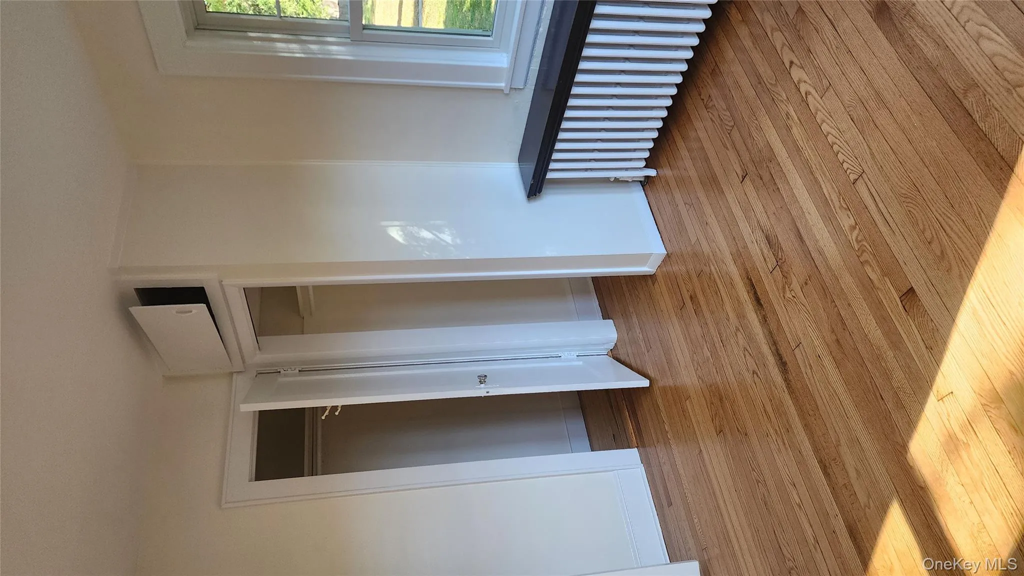 Unfurnished bedroom with radiator heating unit, two closets, and light wood-style floors Unfurnished bedroom with radiator heating unit, two closets, and light wood-style floors