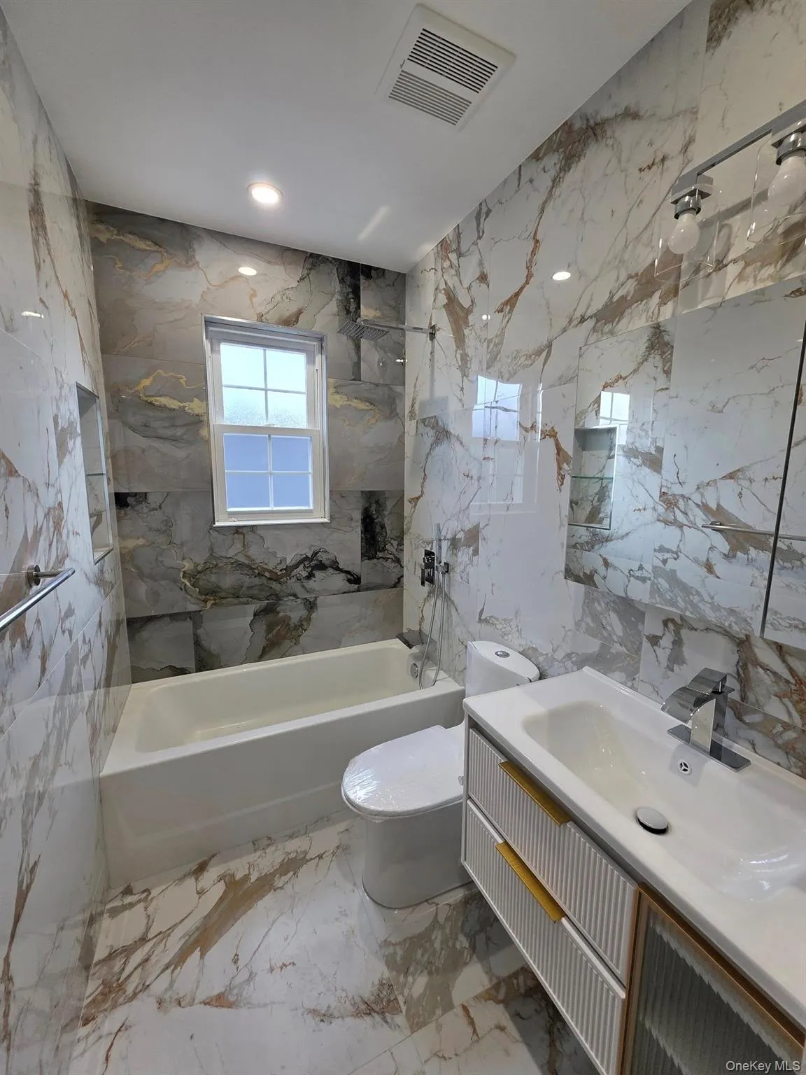 Full bathroom with tile walls, stone wall, vanity, light marble finish floors, and recessed lighting Full bathroom with tile walls, stone wall, vanity, light marble finish floors, and recessed lighting