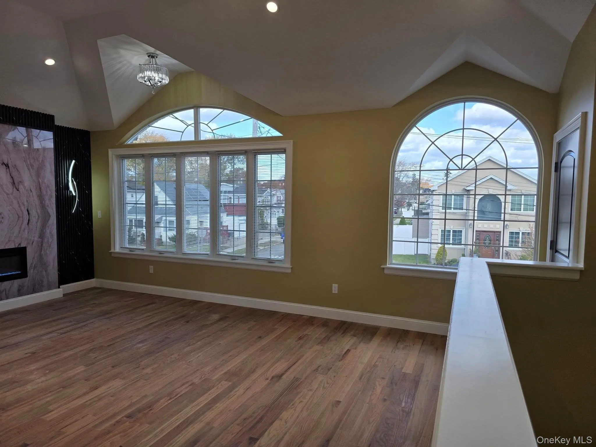 Unfurnished living room featuring lofted ceiling, wood finished floors, a fireplace, and a chandelier Unfurnished living room featuring lofted ceiling, wood finished floors, a fireplace, and a chandelier