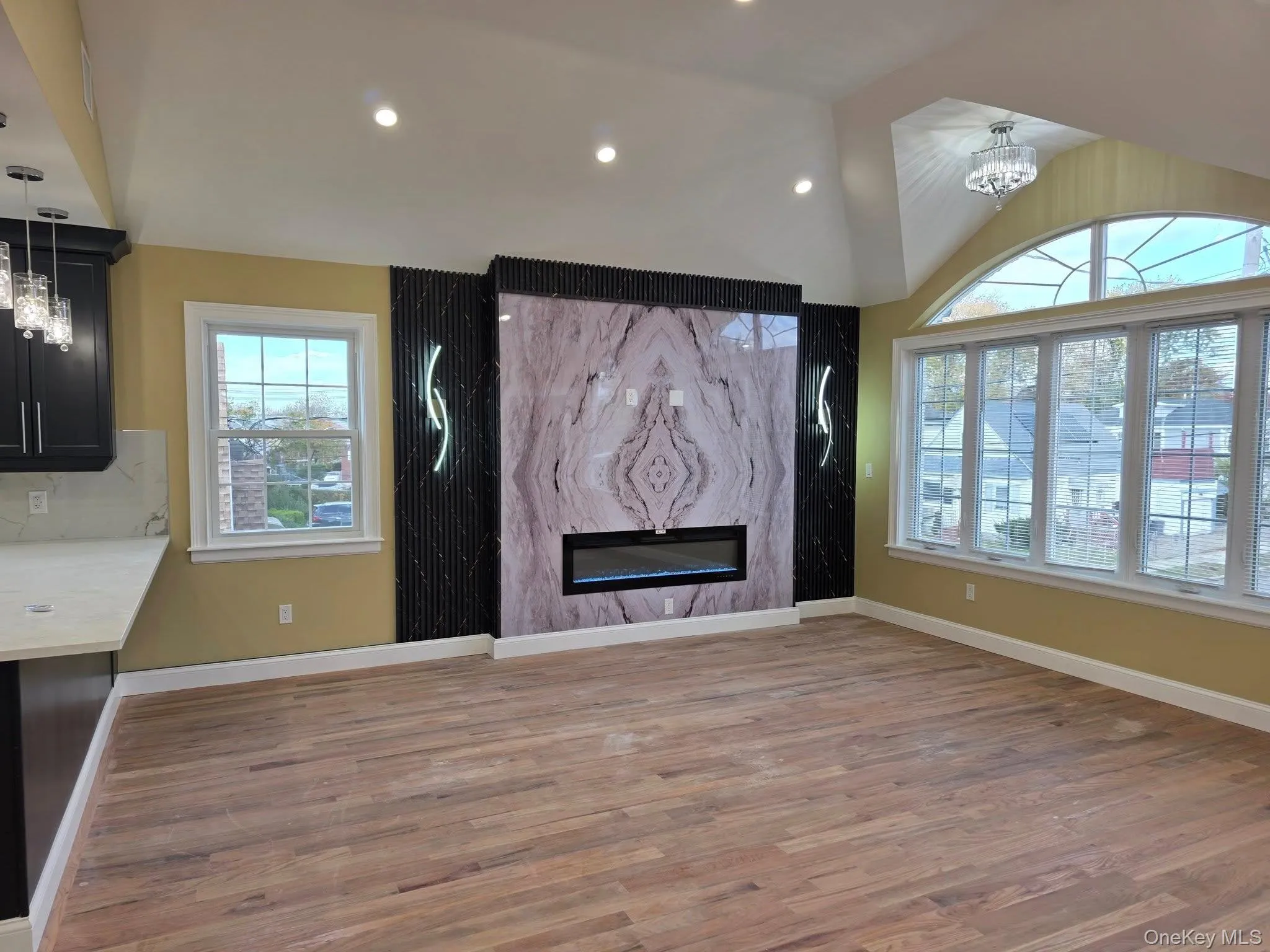 Unfurnished living room featuring a high end fireplace, a chandelier, light wood finished floors, recessed lighting, and lofted ceiling Unfurnished living room featuring a high end fireplace, a chandelier, light wood finished floors, recessed lighting, and lofted ceiling