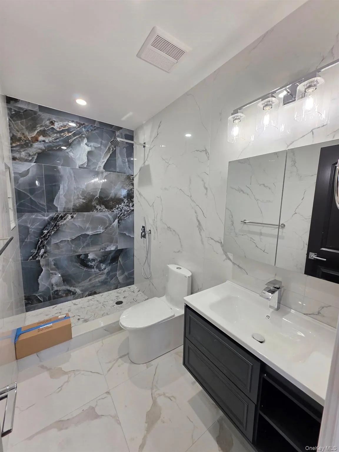 Full bath featuring stone wall, a marble finish shower, vanity, light marble finish floors, and tile walls Full bath featuring stone wall, a marble finish shower, vanity, light marble finish floors, and tile walls