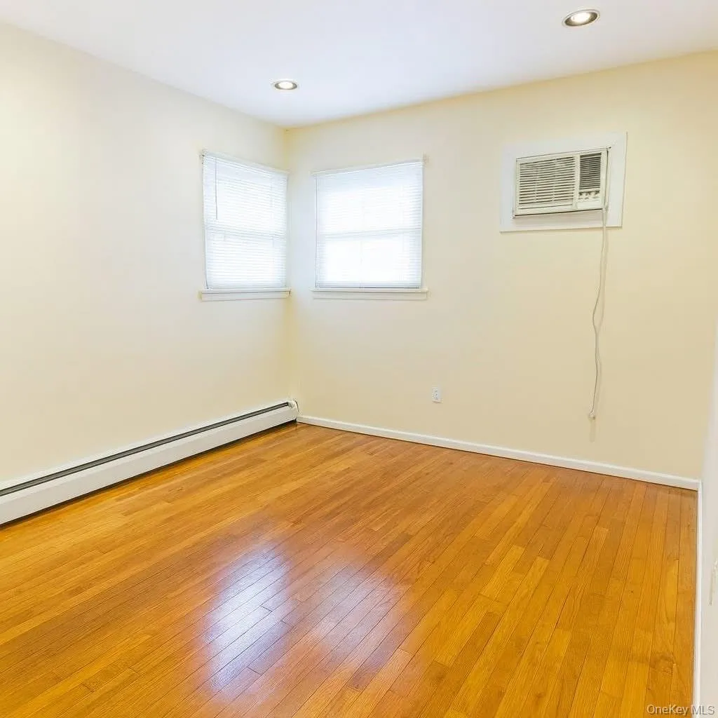 Empty room with light wood-style flooring, recessed lighting, a wall mounted air conditioner, and a baseboard heating unit Empty room with light wood-style flooring, recessed lighting, a wall mounted air conditioner, and a baseboard heating unit