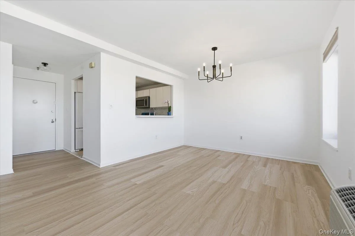 Unfurnished dining area with light wood finished floors, a chandelier, and an AC wall unit Unfurnished dining area with light wood finished floors, a chandelier, and an AC wall unit