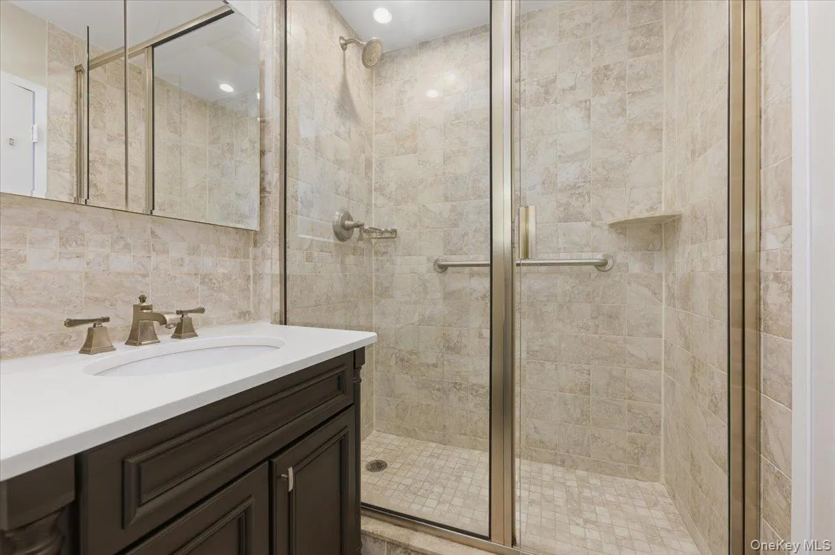 Full bath featuring vanity, a shower stall, and tile walls Full bath featuring vanity, a shower stall, and tile walls