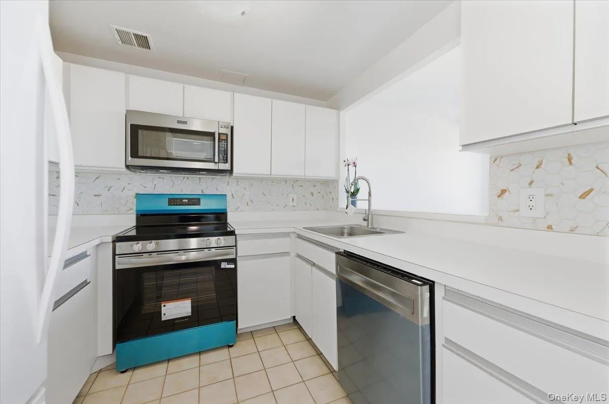 Kitchen featuring appliances with stainless steel finishes, light countertops, and white cabinets Kitchen featuring appliances with stainless steel finishes, light countertops, and white cabinets