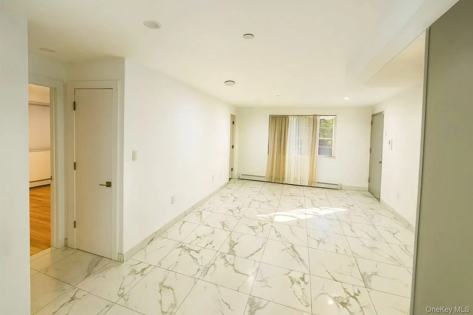 Unfurnished room with light marble finish flooring, a baseboard radiator, and recessed lighting Unfurnished room with light marble finish flooring, a baseboard radiator, and recessed lighting