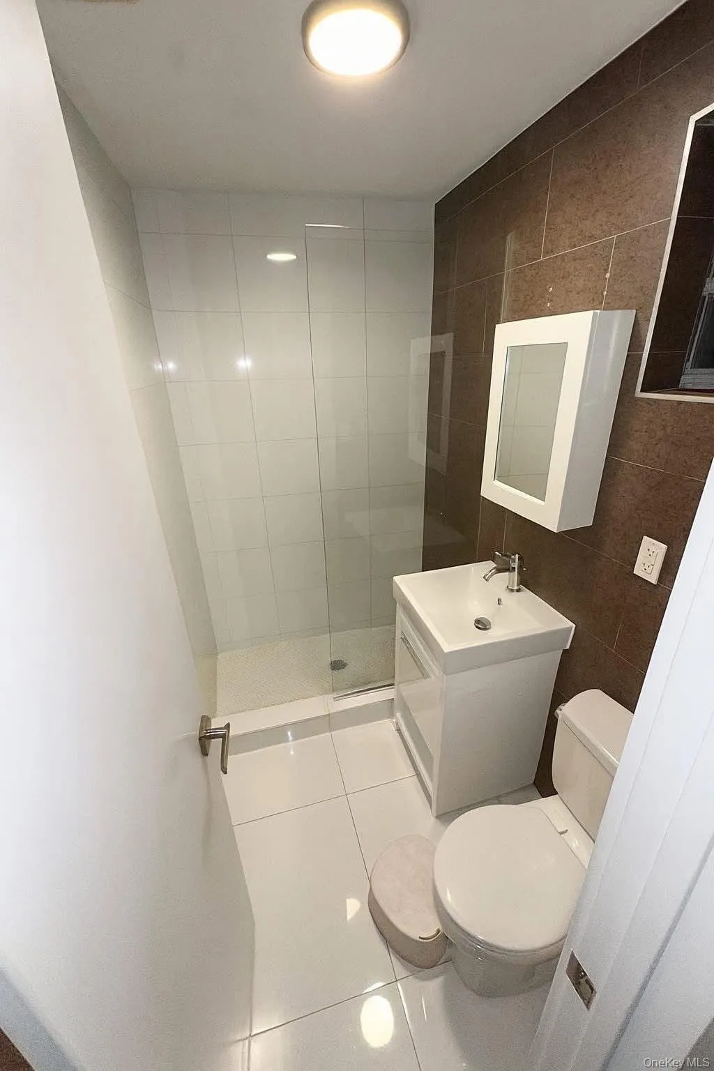 Bathroom with light tile patterned floors, vanity, tile walls, and a stall shower Bathroom with light tile patterned floors, vanity, tile walls, and a stall shower
