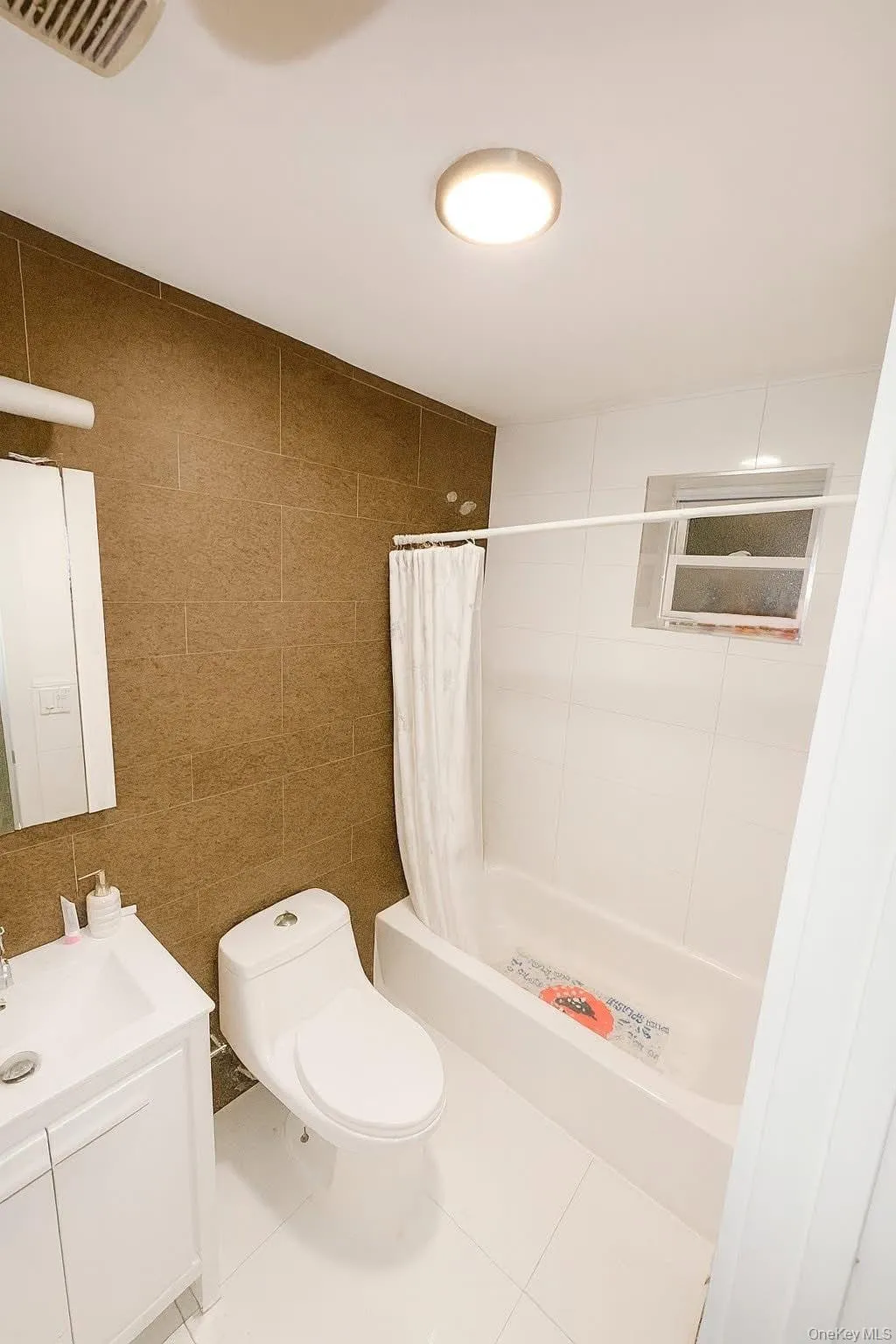 Full bath with tile walls, vanity, tile patterned floors, and tiled shower / bath Full bath with tile walls, vanity, tile patterned floors, and tiled shower / bath