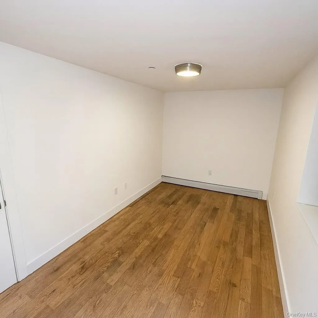 Spare room featuring wood finished floors and a baseboard heating unit Spare room featuring wood finished floors and a baseboard heating unit