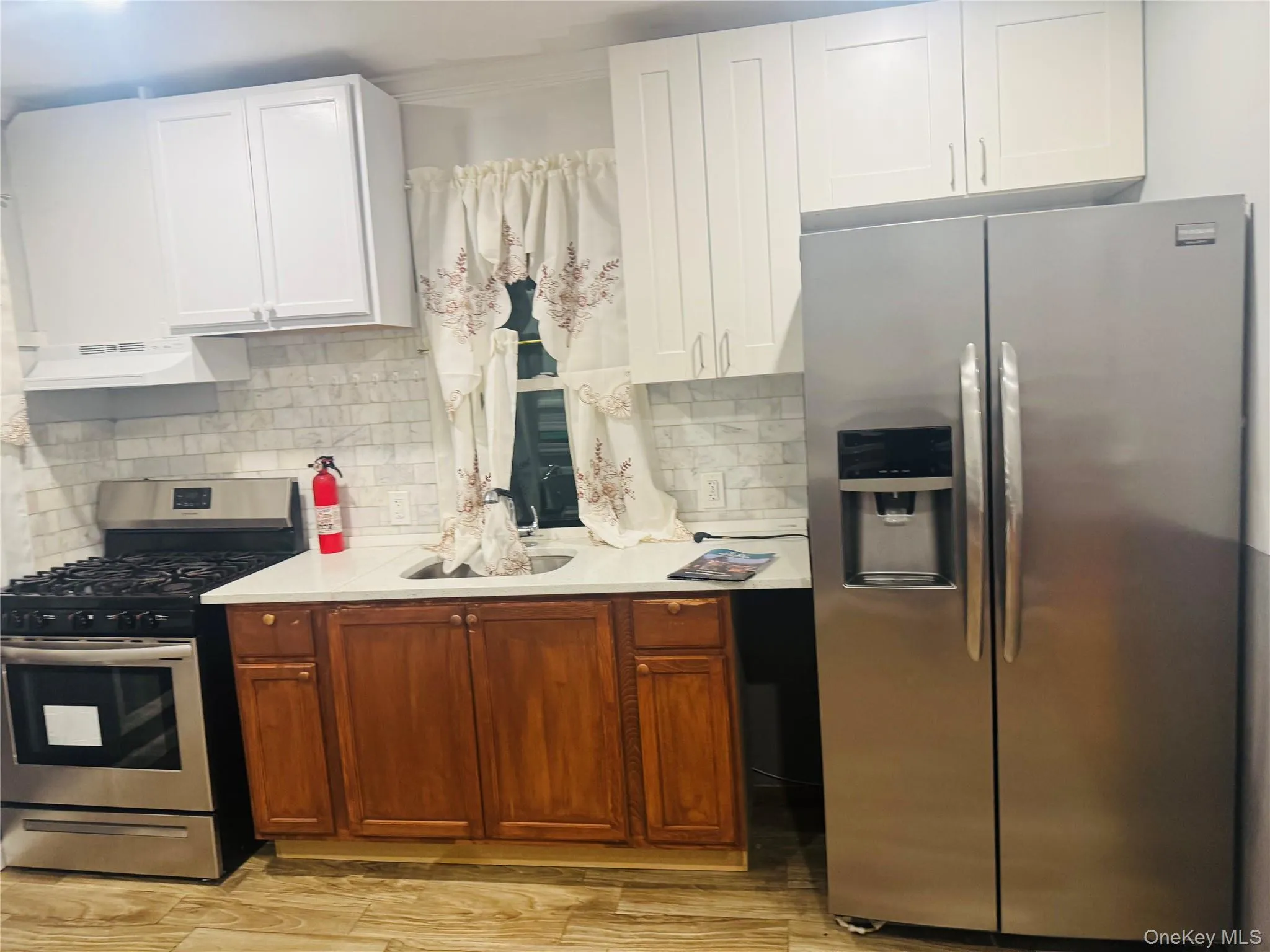 Kitchen featuring appliances with stainless steel finishes, white cabinets, decorative backsplash, and crown molding Kitchen featuring appliances with stainless steel finishes, white cabinets, decorative backsplash, and crown molding