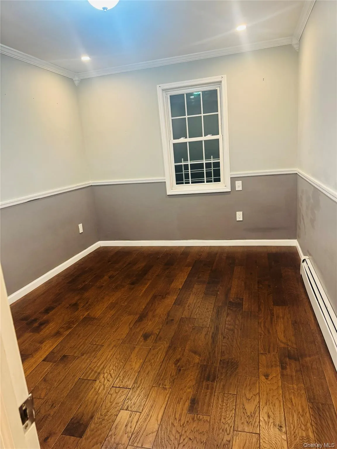 Spare room with a baseboard radiator, dark wood-type flooring, recessed lighting, and ornamental molding Spare room with a baseboard radiator, dark wood-type flooring, recessed lighting, and ornamental molding