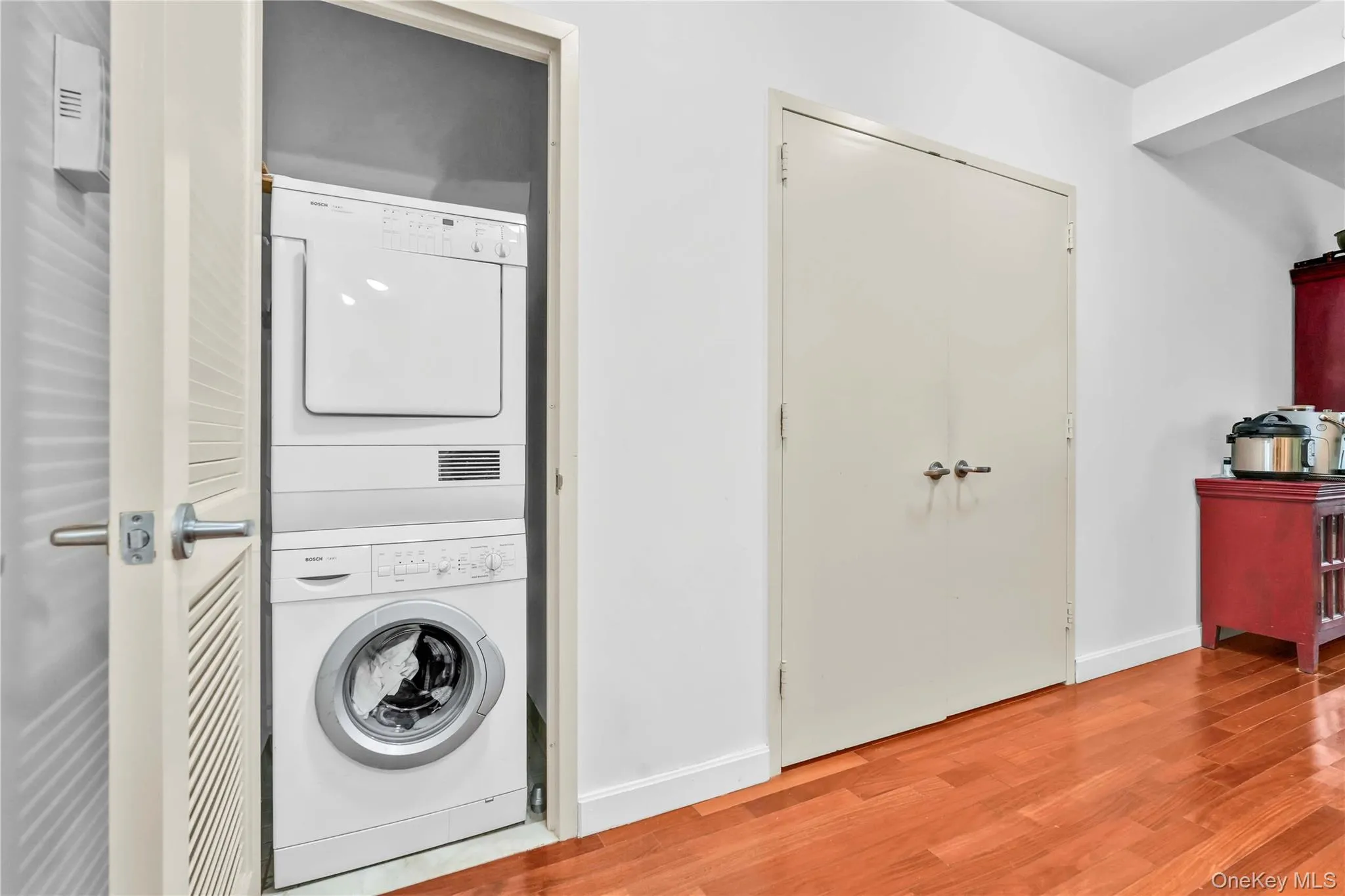 Laundry area featuring stacked washing machine and dryer and light wood-style flooring Laundry area featuring stacked washing machine and dryer and light wood-style flooring