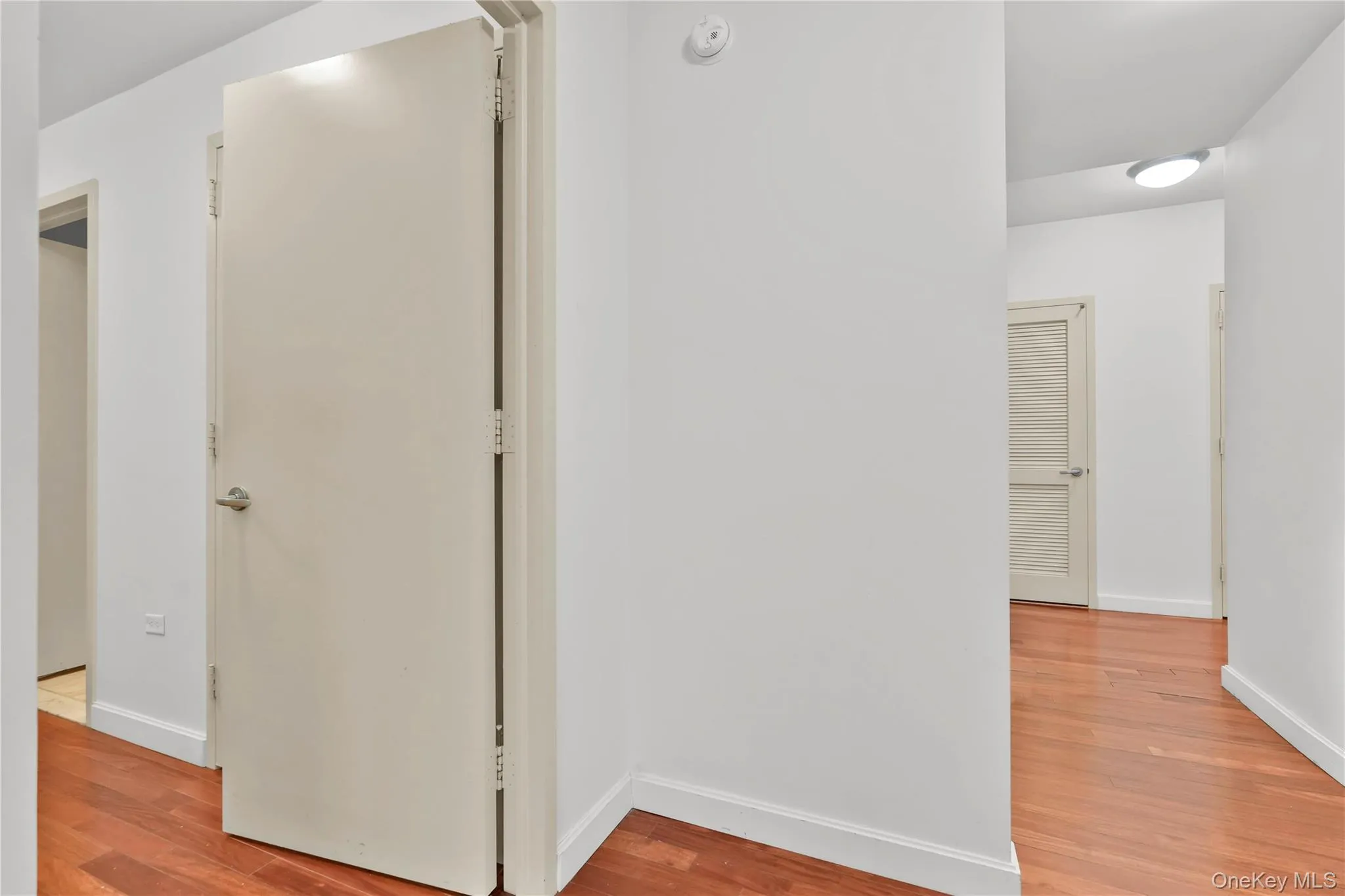 Corridor featuring light wood-style flooring and baseboards Corridor featuring light wood-style flooring and baseboards