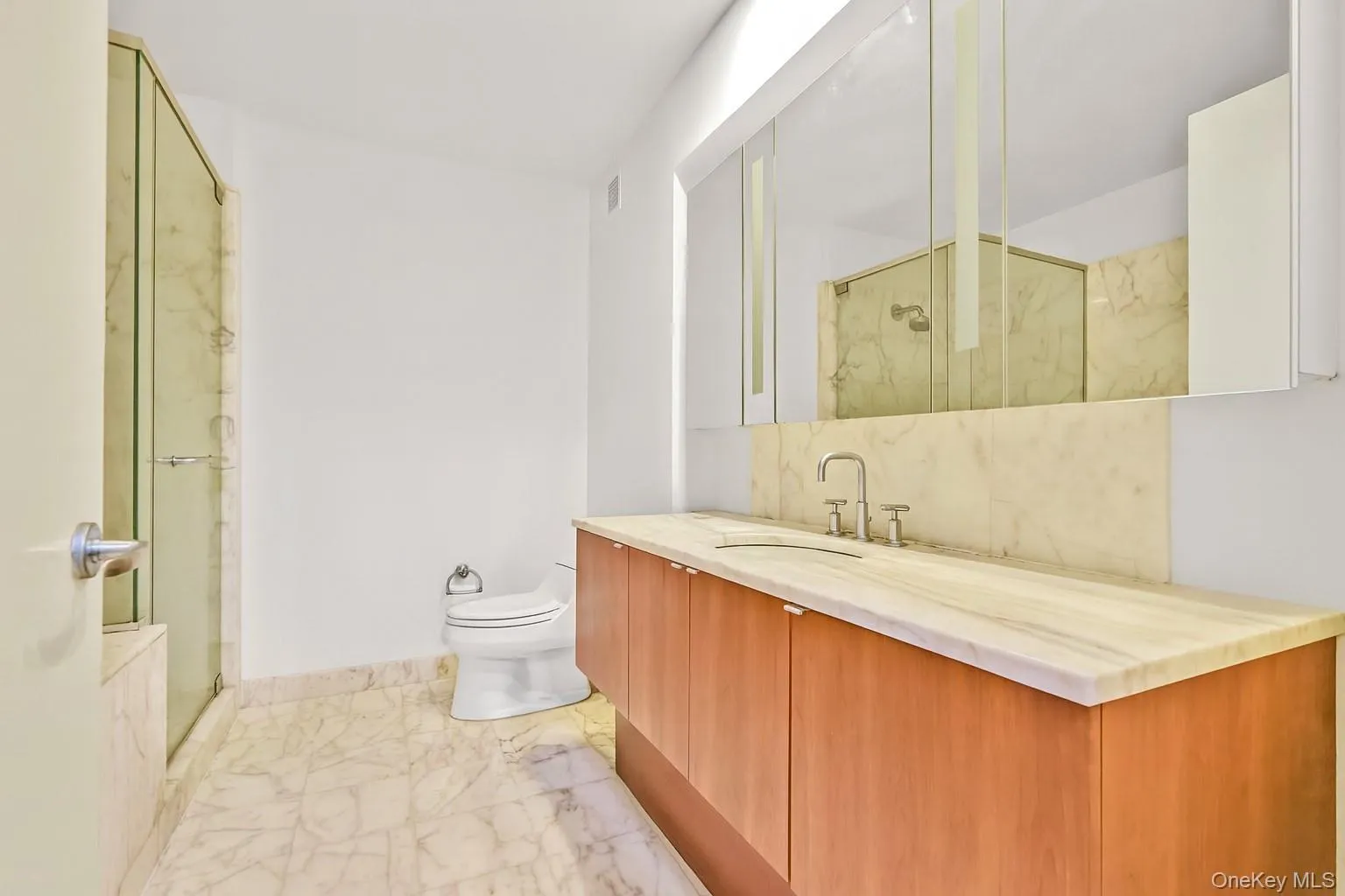 Full bathroom featuring vanity, a marble finish shower, and light marble finish flooring Full bathroom featuring vanity, a marble finish shower, and light marble finish flooring