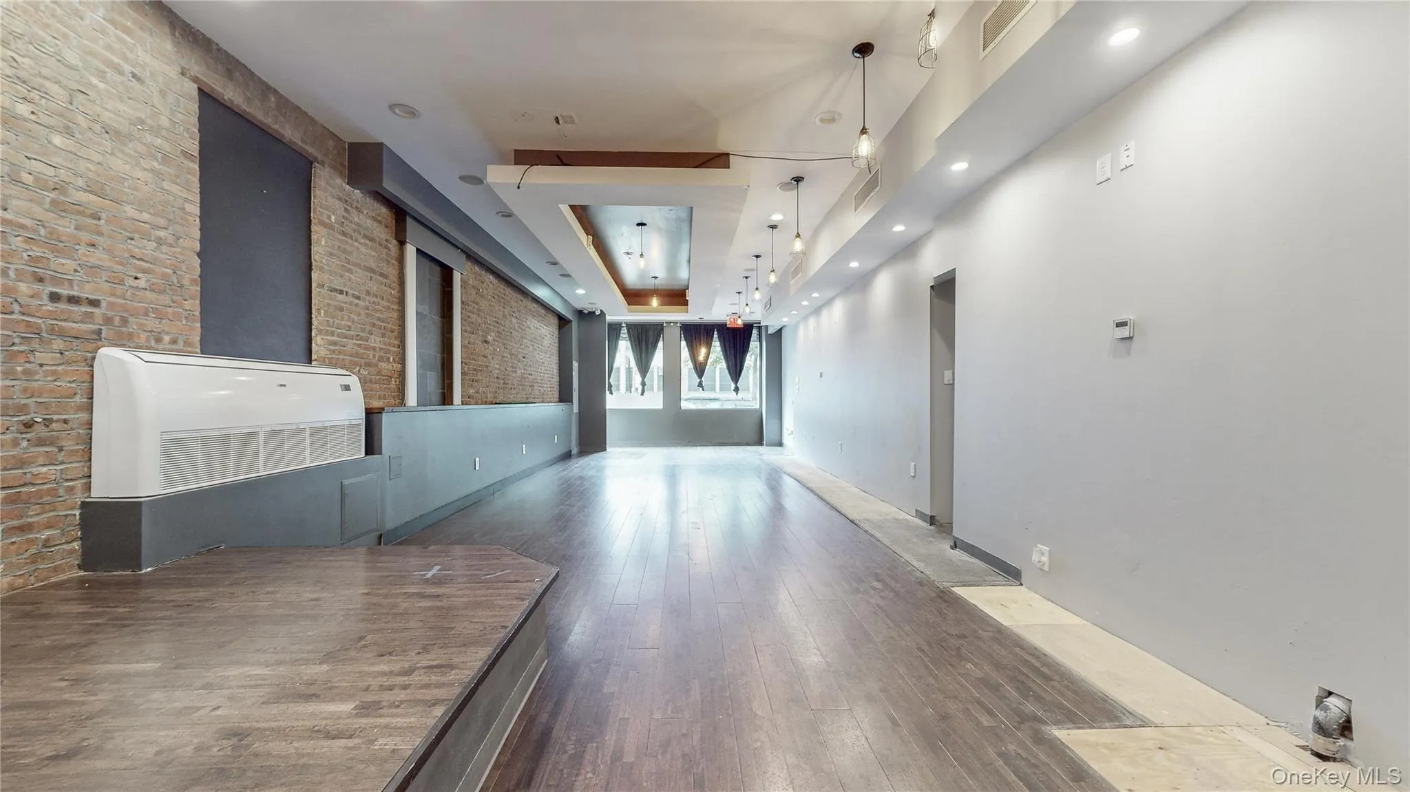 Hallway with brick wall, recessed lighting, and hardwood / wood-style flooring Hallway with brick wall, recessed lighting, and hardwood / wood-style flooring