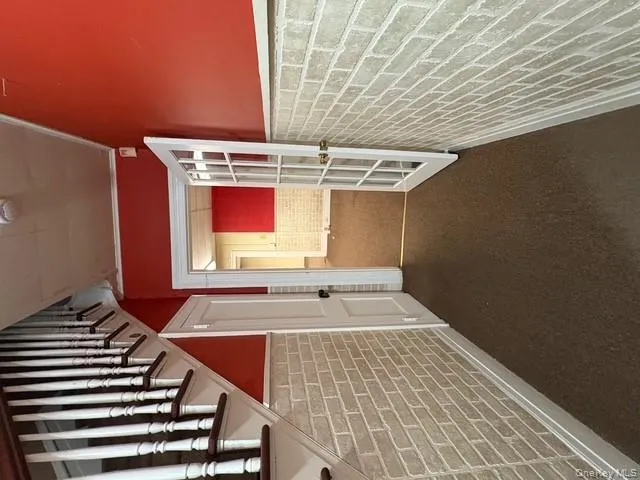 Hallway with brick wall, wainscoting, stairway, dark colored carpet, and ornamental molding Hallway with brick wall, wainscoting, stairway, dark colored carpet, and ornamental molding