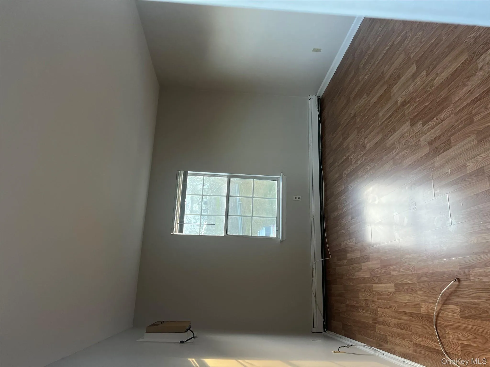 Empty room with wood finished floors and a baseboard heating unit Empty room with wood finished floors and a baseboard heating unit