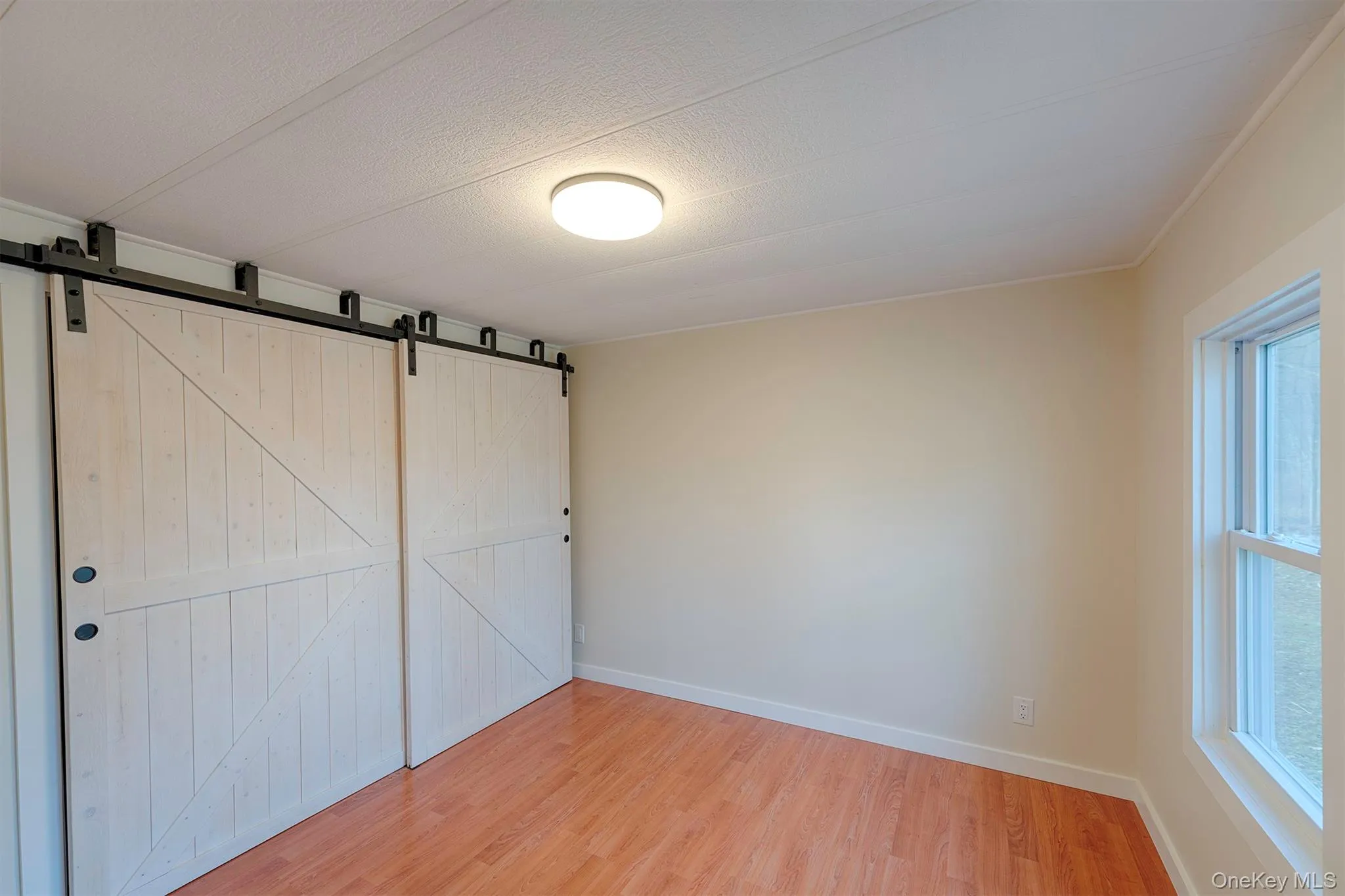 Unfurnished bedroom with a closet, light wood-style flooring, and a textured ceiling Unfurnished bedroom with a closet, light wood-style flooring, and a textured ceiling