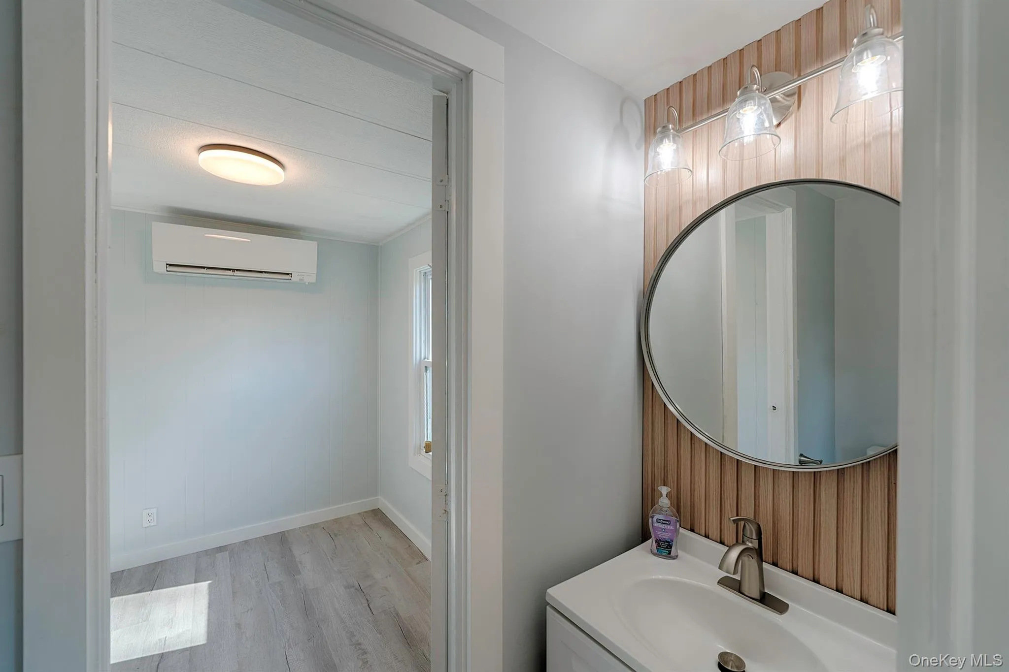Bathroom featuring a wall mounted air conditioner, light wood-style floors, and vanity Bathroom featuring a wall mounted air conditioner, light wood-style floors, and vanity