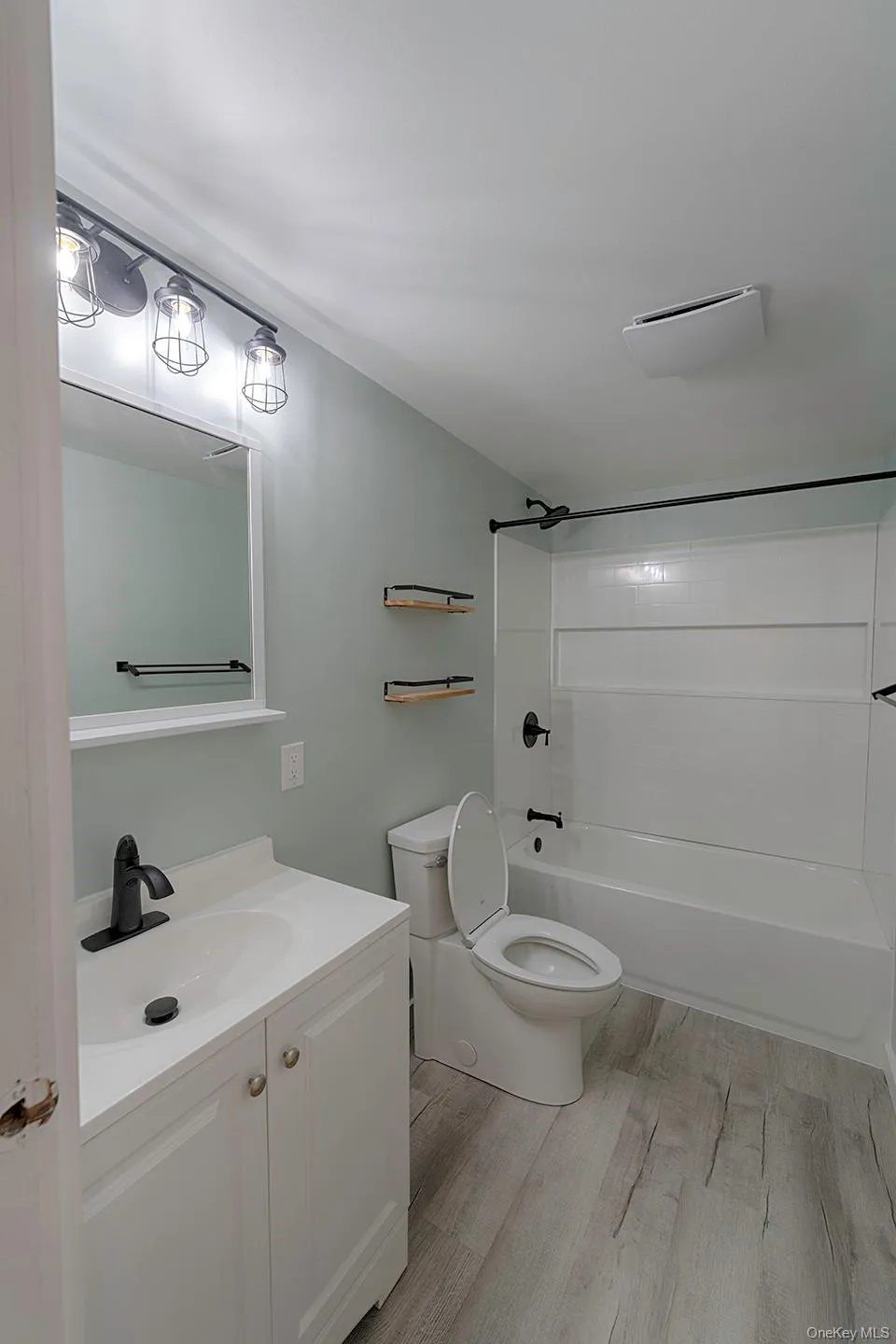 Bathroom with bathtub / shower combination, vanity, and light wood-style flooring Bathroom with bathtub / shower combination, vanity, and light wood-style flooring