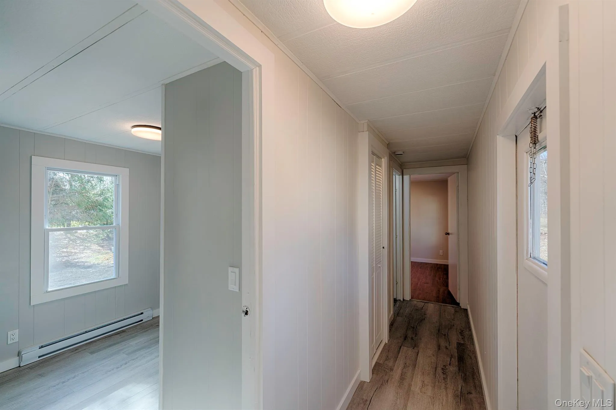 Hall featuring wood finished floors and baseboard heating Hall featuring wood finished floors and baseboard heating
