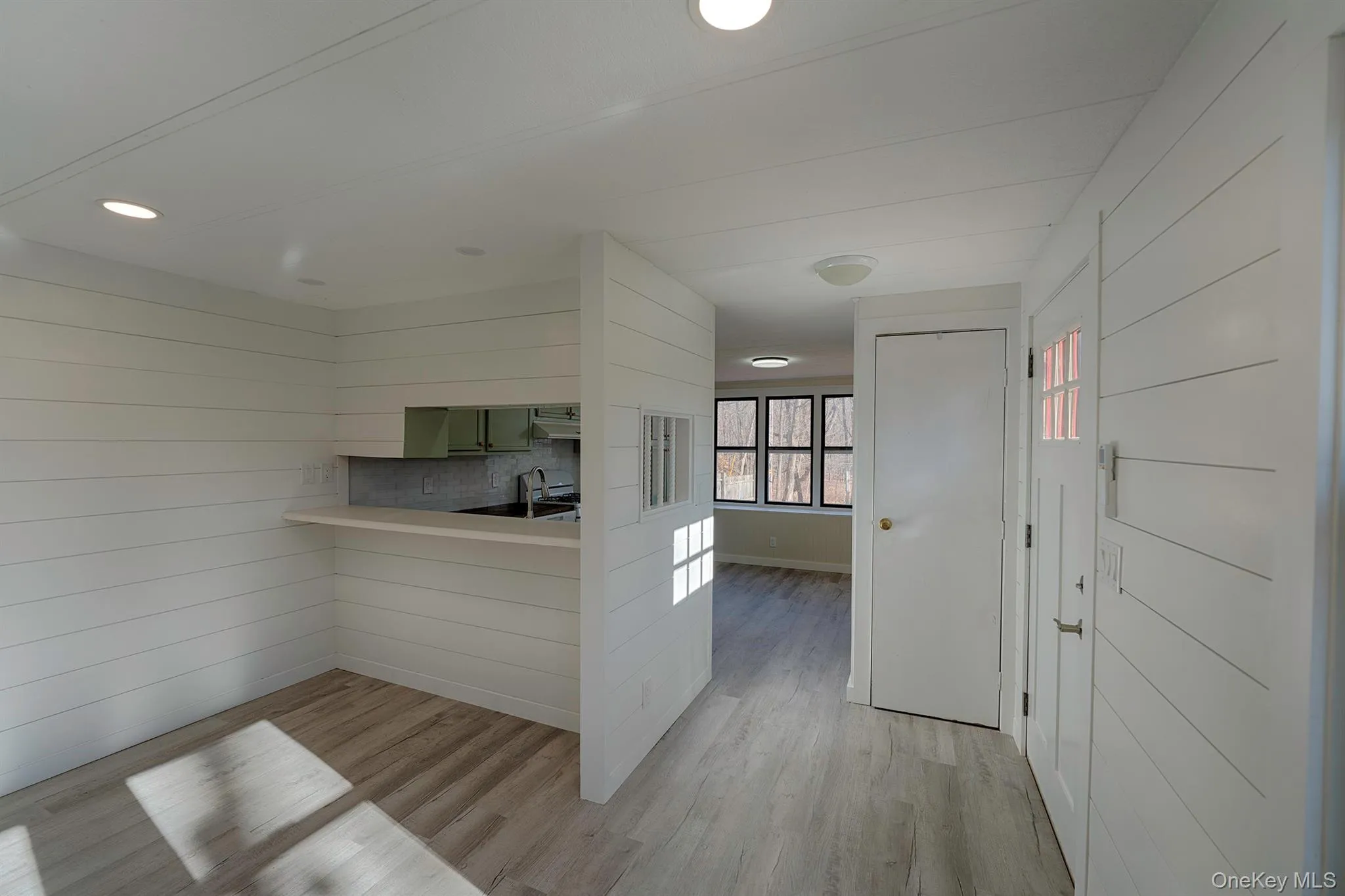 Kitchen with light wood finished floors, light countertops, wood walls, and a peninsula Kitchen with light wood finished floors, light countertops, wood walls, and a peninsula