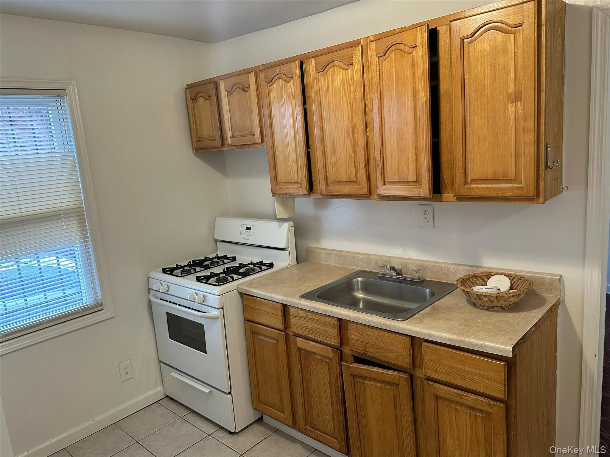 Kitchen with gas range gas stove, light countertops, brown cabinets, and light tile patterned floors Kitchen with gas range gas stove, light countertops, brown cabinets, and light tile patterned floors