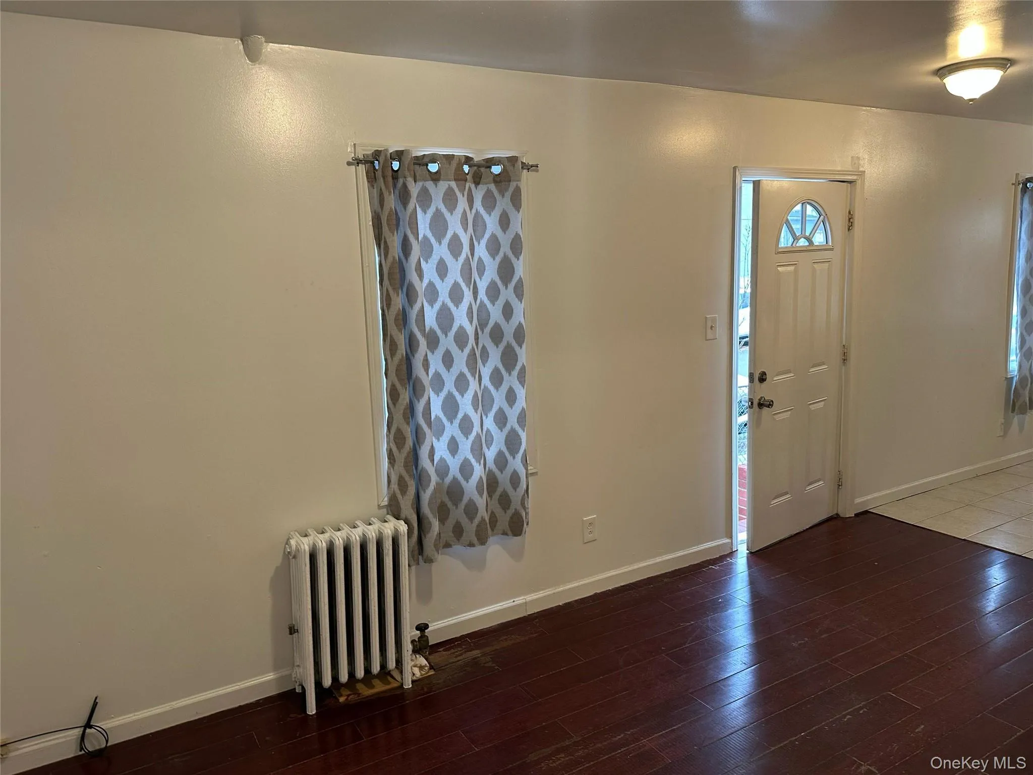 Entrance foyer with radiator heating unit and dark wood-type flooring Entrance foyer with radiator heating unit and dark wood-type flooring