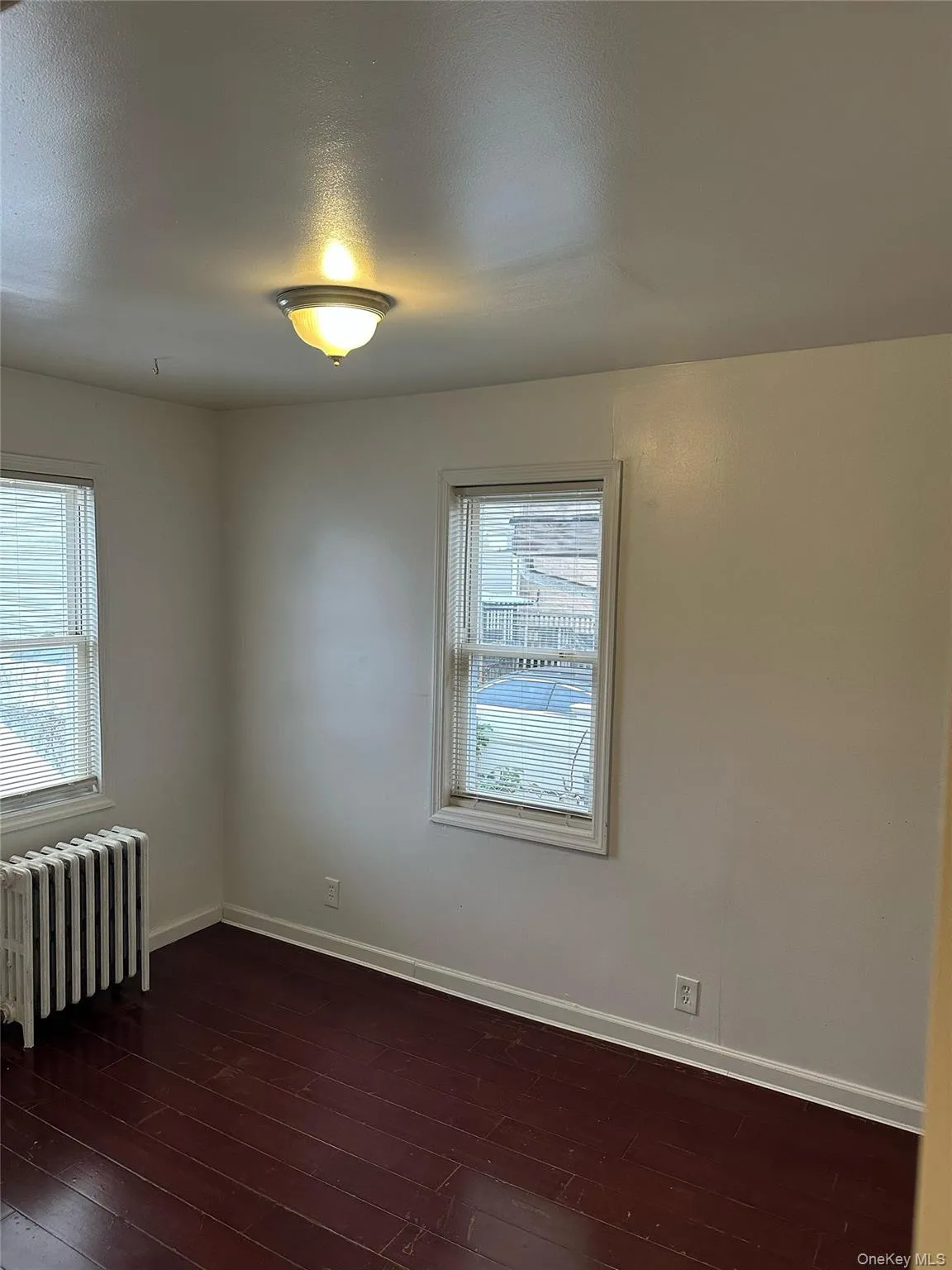 Spare room with radiator and dark wood-type flooring Spare room with radiator and dark wood-type flooring