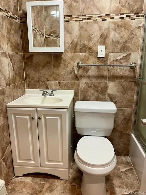 Bathroom with tile walls, vanity, and stone tile flooring Bathroom with tile walls, vanity, and stone tile flooring